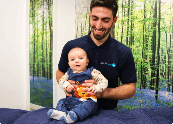 A bodytonic employee holding a baby.